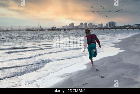Nicht erkennbarer Mann, der während des Sonnenuntergangs am Strand läuft Stockfoto