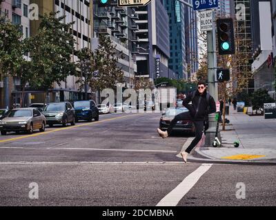 Energiegeladener, glücklicher junger Mann, der in der modernen Stadt auf dem Fußgängerüberweg springt Stockfoto