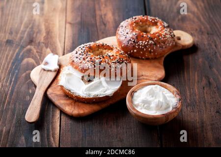 Vollkorn-Bagels mit Frischkäse auf Holzbrett, selektiver Fokus Stockfoto