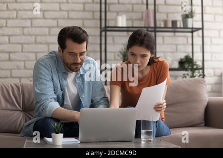 Fokussierte junge verheiratete Paar Blick auf Computer-Bildschirm, Planung Budget. Stockfoto