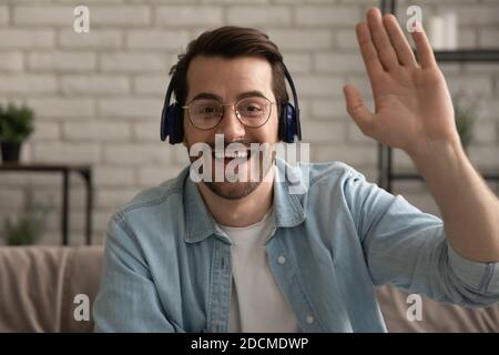 Lächelnder junger Mann begrüßt Freunde bei Online-Videokonferenz. Stockfoto