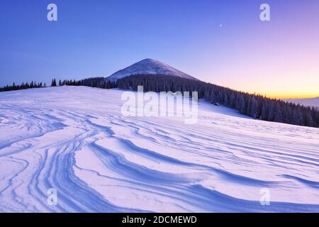 Winterwald. Toller Sonnenaufgang. Hohe Berge mit schneeweißen Gipfeln. Ein Panoramablick auf die mit Frostbäumen bedeckten Schneeverwehungen. Naturland Stockfoto