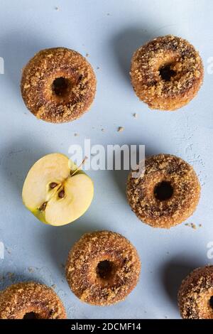 Nahaufnahme von hausgemachten gebackenen Apfelmost-Donuts mit Zuckerzuck und Apfelschnitt auf blauer Strukturoberfläche. Bereit, Snack zu essen. Kleine Charge Lebensmittel mit Zutat. Di Stockfoto