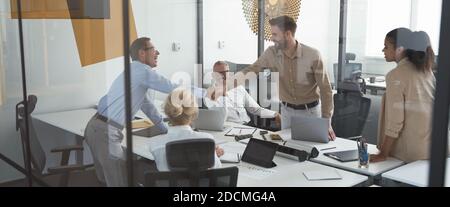 Zwei erfolgreiche Geschäftsleute schütteln die Hände, während ein Treffen mit Kollegen im Konferenzraum im modernen Büro Stockfoto