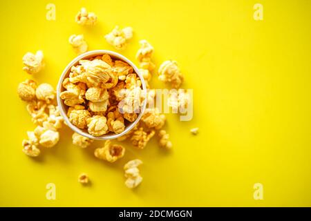 Draufsicht auf Popcorn in Papierglas auf gelbem Hintergrund Mit Kopierbereich