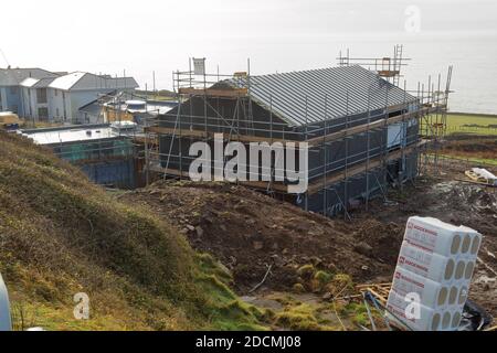 Die Bauarbeiten am Dorfhaus bei Ogmore am Meer gehen weiter und man kann sehen, wie das Dach fast vollständig ist und die Außenarbeiten kurz vor der Fertigstellung sind. Stockfoto