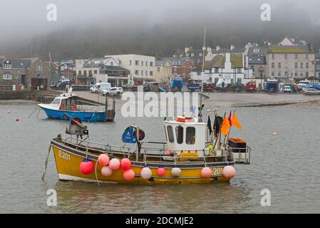 Fischerboote und Vergnügungsboote im Hafen von Lyme Regis an der Jurassic Coast in Dorset England an einem nebligen Wintertag. Stockfoto