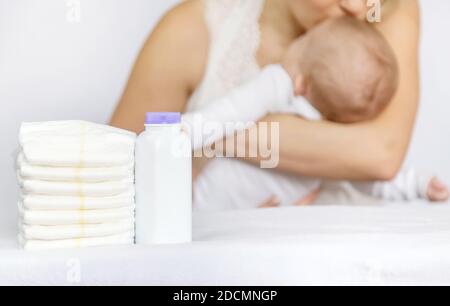 Mutter ändert die Windel des Babys auf einem hellen Hintergrund. Selektiver Fokus. Menschen. Stockfoto