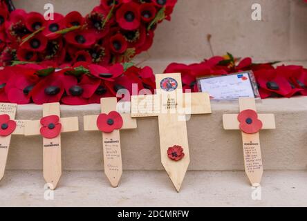 Tribute Holzkreuze, um den gefallenen Kriegsveteranen im Cenotaph Respekt zu zollen, mit roten Mohnkränzen im Hintergrund. London Stockfoto
