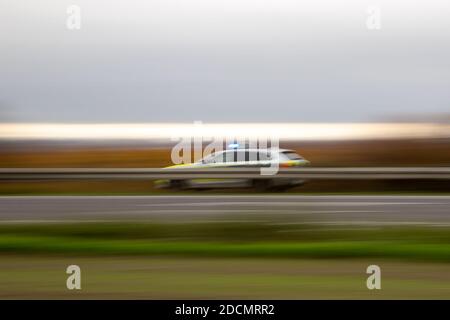 Deutscher Polizeiwagen in Bewegung auf einer Autobahn hinter Leitplanken, im Freien, Alarmanlage an Stockfoto