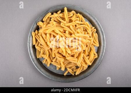 Strozzapreti, italienische Pasta in Metallplatte auf einem grauen Tisch. Stockfoto