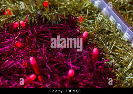 Nahaufnahme auf goldenen und rosa Girlande-Bändern mit roten Lichtern. Weihnachten bunte Dekoration abstrakte Textur Konzept Stockfoto