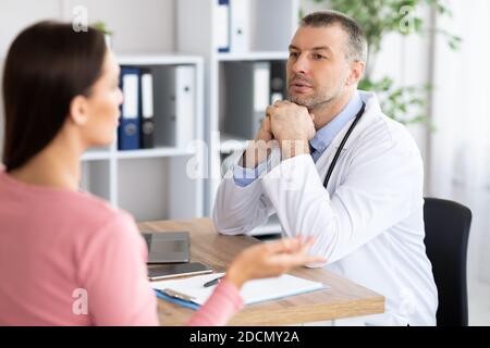 Männlicher erfahrener Arzt im Gespräch mit seiner Patientin Stockfoto