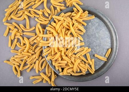 Strozzapreti, italienische Pasta in Metallplatte auf einem grauen Tisch. Abstraktes Essen Hintergrund Stockfoto