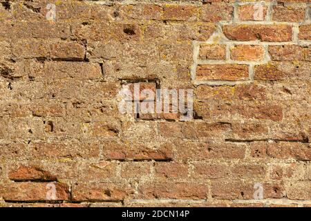 Eine rote Wand mit beschädigten Ziegeln Stockfoto