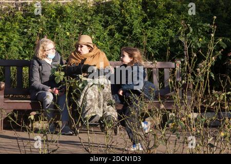 UK Weather, London, 22 November 2020: An einem sonnigen Sonntag in London strömen Menschen in den Holland Park, wo Menschen auf Bänken sitzen und die Sonne genießen.nur wenige Menschen trugen Gesichtsmasken, aber die meisten machten einen Versuch der sozialen Distanzierung. Für morgen (Montag) sind Ankündigungen über ein neues Tier-System von Covid-Restriktionen geplant, das nach Abschluss der aktuellen Sperre am 2. Dezember eingeführt werden soll. Anna Watson/Alamy Live News Stockfoto