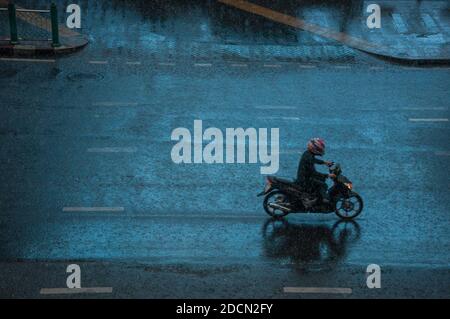 Ein Motorradfahrer fährt an einem Regentag entlang der Straße. Stockfoto