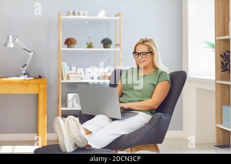 Casual weibliche blonde Manager arbeiten auf Laptop sitzen auf bequemen Stuhl in modernen hellen Büro. Stockfoto