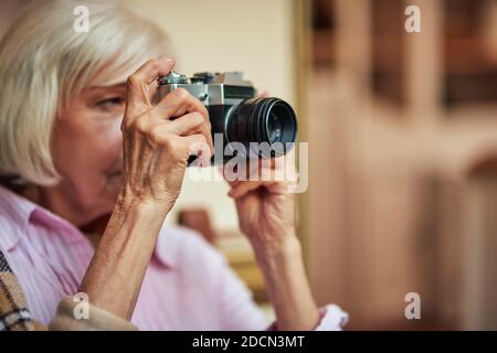 Nahaufnahme der grauhaarigen älteren Frau mit Kamera und gehen, um Foto zu machen. Lifestyle-Konzept. Speicherplatz kopieren Stockfoto