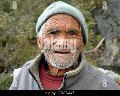 Sehr alter zahnloser Nepalesischer Sherpa-Mann mit tiefen Falten überall in seinen einlebenden Gesichtenposen für die Kamera auf dem Everest Base Camp Trek. Stockfoto