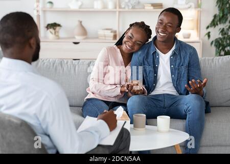 Familienberatung. Junges glückliches schwarzes Paar, das auf Couch im Büro des Psychotherapeuten sitzt Stockfoto