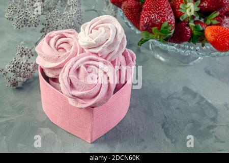 Frische handgemachte Marshmallows in leichter Stimmung. Nahaufnahme eines rosa Marshmallows in einer rosa herzförmigen Geschenkbox.Fruchtmarmelibe mit frischen Erdbeeren Stockfoto