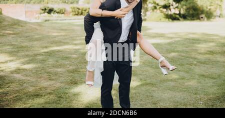 Bräutigam trägt die Braut auf dem Rücken, Brautpaar Spaß zusammen. Hochzeitsfotografie Konzept. Stockfoto