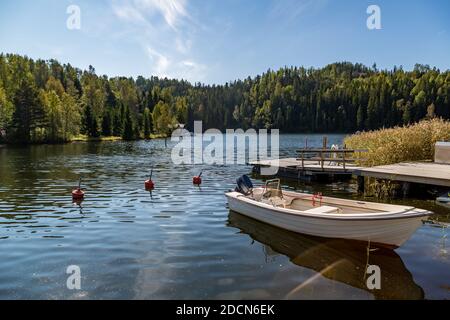 Kleines Boot mit Außenbordmotor, das an einem warmen und sonnigen Sommertag an einem hölzernen Pier festgemacht ist. Stockfoto