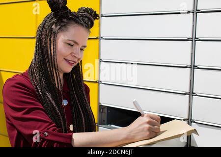 Er sucht geistig nach der genauen Korrespondenzadresse. Er schreibt mit einem weißen Stift auf einen Umschlag. Schreibt den Adressaten. Stockfoto