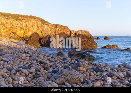 Goldenes frühmorgendliches Sonnenlicht reflektiert von den Klippen am Trow Beach, South Shields, Tyne und Wear. Stockfoto