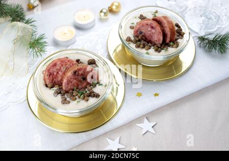 Scheiben Cotechino mit Linsencreme auf dem Teller serviert. Weihnachtsschmuck. Italienisches Essen. Selektiver Fokus Stockfoto