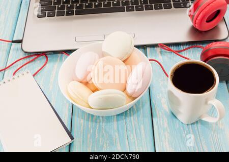 Offener Laptop mit weißem Kaffeetup, Marshmallows und roten Kopfhörern Stockfoto