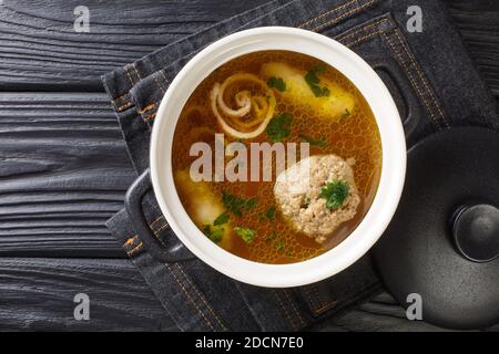 Köstliche Wiener Rindsuppe auf Basis von Rinderbrühe mit Knödeln aus der Nähe in einem Topf auf dem Tisch. Horizontale Ansicht von oben Stockfoto