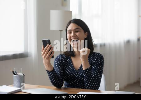 Überglücklich asiatische Frau lesen gute Nachrichten, Telefon halten, Erfolg feiern Stockfoto