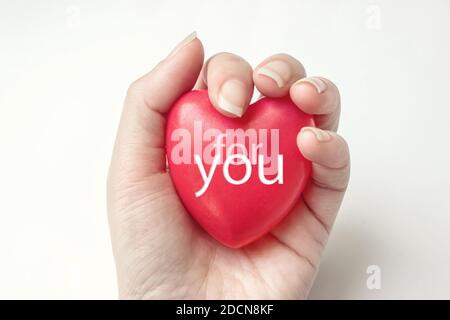 Hand hält rotes Herz mit Text FÜR SIE, Gesundheit, spenden und Familienversicherung Konzept. Welt Herz Gesundheit Tag Idee. Komposition für Valentinstag, Stockfoto