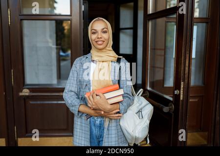 Arabisches Mädchen mit Büchern posiert am Eingang der Universität Stockfoto