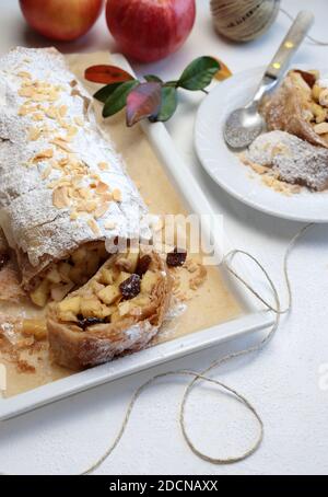 Hausgemachter Apfelstrudel mit Phyllo-Gebäck, Zimt, Sultaninen, Mandeln auf weißem Hintergrund. Selektiver Fokus Stockfoto