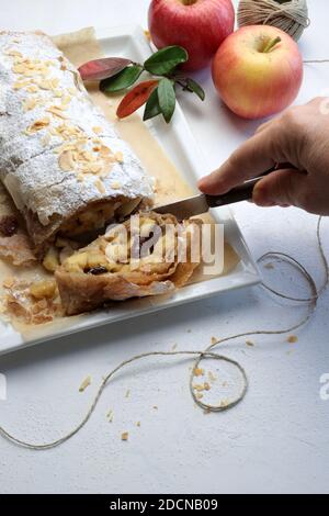 Hausgemachter Apfelstrudel mit Phyllo-Gebäck, Zimt, Sultaninen, Mandeln auf weißem Hintergrund. Selektiver Fokus Stockfoto