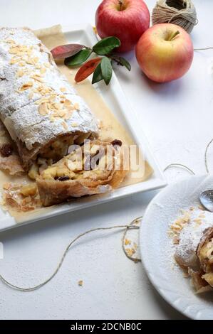 Hausgemachter Apfelstrudel mit Phyllo-Gebäck, Zimt, Sultaninen, Mandeln auf weißem Hintergrund. Selektiver Fokus Stockfoto