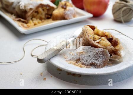 Hausgemachter Apfelstrudel mit Phyllo-Gebäck, Zimt, Sultaninen, Mandeln auf weißem Hintergrund. Selektiver Fokus Stockfoto