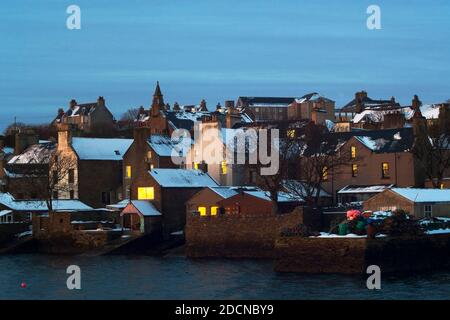 Winter Sonnenaufgang mit Schnee auf Dächern aus traditionellem Stein gebaut Häuser in schottischer Stadt auf Orkney Inseln Stockfoto