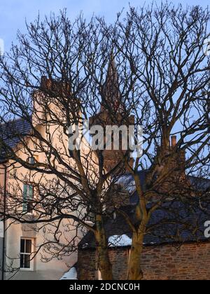 Baumzweige vor traditionellen schottischen Kleinstadtgebäuden Im Winter Szene mit Kirchturm Stockfoto