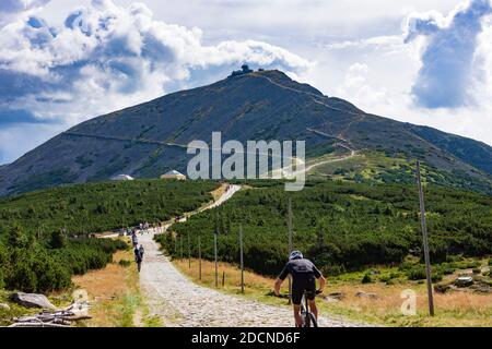 Karpacz (Krummhübel): Hauptkammweg 'Polish-Czech Friendship Trail', Blick auf den Berg Snezka oder Sniezka (Schneekoppe), Mountainbiker bei einem Wettbewerb Stockfoto