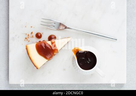 Käsekuchen mit gesalzener Karamellsauce auf Marmorplatte, Draufsicht Stockfoto