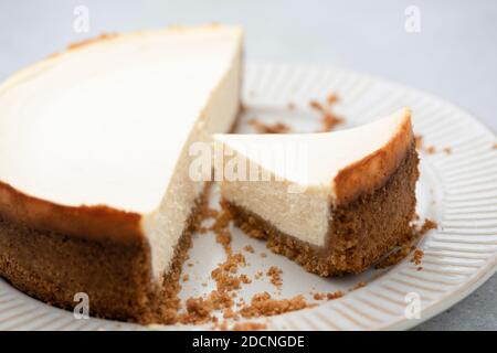 Einfacher New yorker Käsekuchen mit ausgeschnittener Scheibe auf einem Teller, Nahaufnahme. Leckerer Käsekuchen Stockfoto