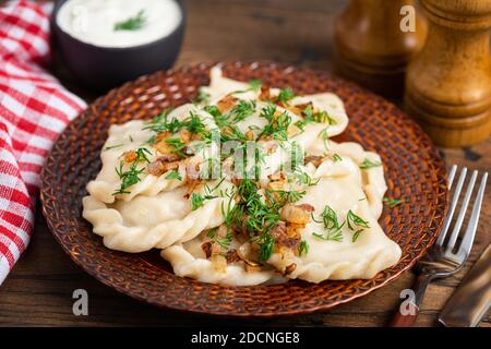 Polish Pierogi oder Vareniki gefüllt mit Kartoffeln serviert mit gebratener Zwiebel und Dill. Kartoffelknödel Stockfoto