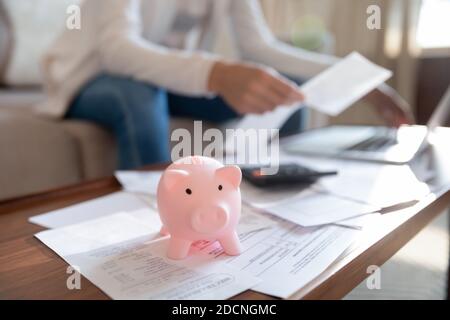 Niedliche Sparschwein auf dem Schreibtisch des Heimbüros mit Dokumenten übersät stehen Stockfoto