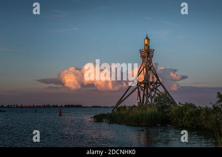 Old Hoorn Harbour Lighthouse kurz nach Sonnenuntergang mit einer beleuchteten Wolke im Hintergrund. Stockfoto