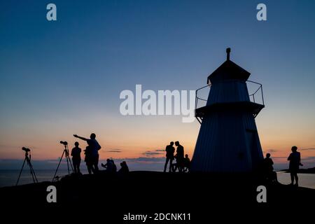 BUA, SCHWEDEN - 27. JULI 2018: Kleine Menschenmenge, die sich kurz nach Sonnenuntergang am Leuchtturm Krogstadsudda versammelt, um die totale Mondfinsternis zu sehen und zu fotografieren. Stockfoto