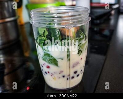 Smoothie. Alle Zutaten für einen hausgemachten Smoothie, einschließlich Himbeeren, Heidelbeeren, Spinatblätter und griechischem Joghurt. Stockfoto